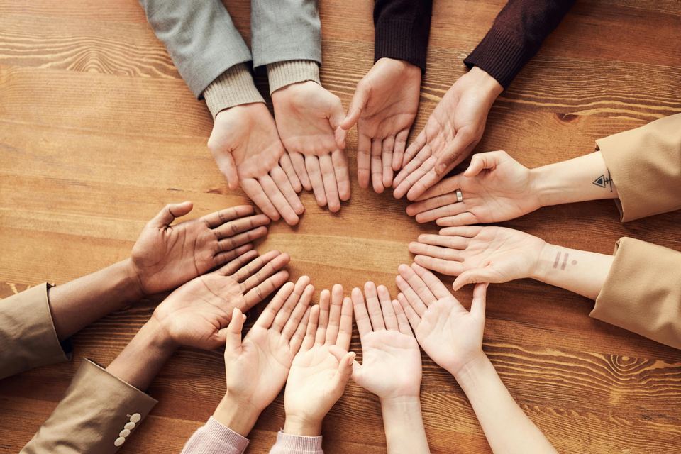 Team members’ hands joined in a circle on a wooden table